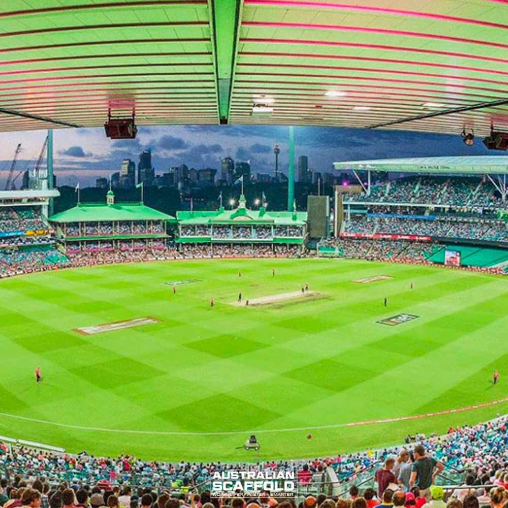 Sydney Cricket Ground, illuminated by floodlights with a vibrant green field and spectators in the stands